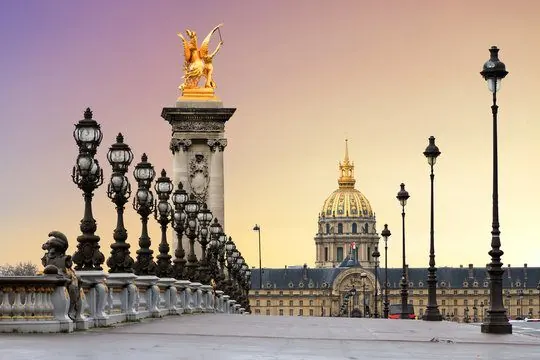 Pont Alexandre III lamps and gilded statue with the golden dome of Les Invalides at dusk, Paris